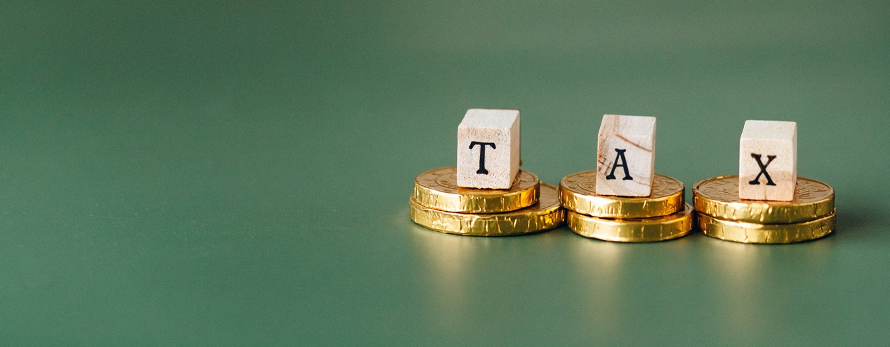 Wooden letters of a word Tax that is placed over gold coins