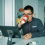 A man drinking coffee while working overtime