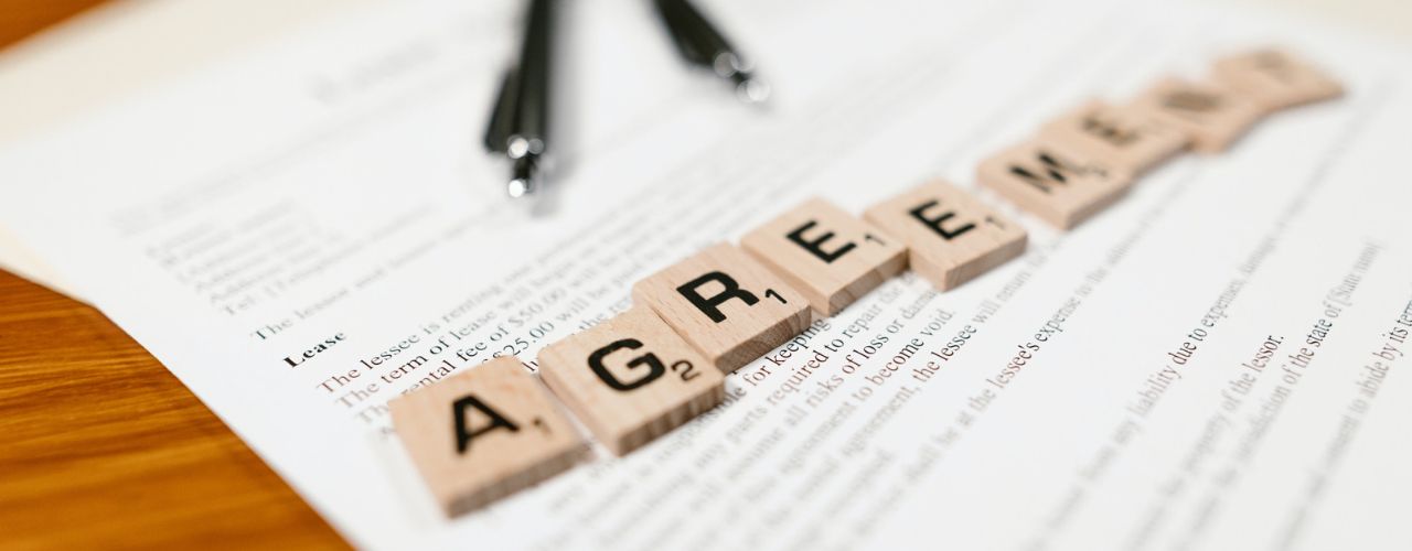 scrabble letters forming the word agreement that is placed on top of a document