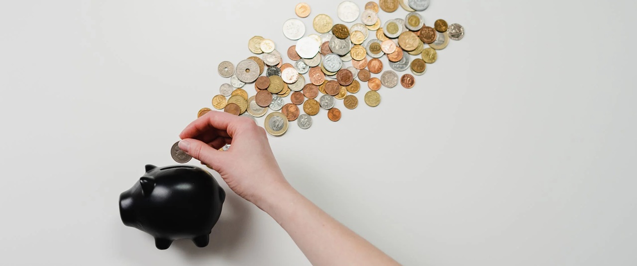 A person inserting coins inside a black piggy bank